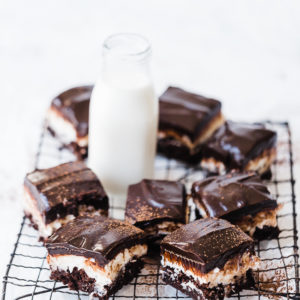 Almond joy brownies on a cooling rack, with a glass of milk.