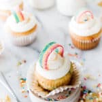funfetti cupcake with white frosting and sour rainbow candy on top in rainbow shape