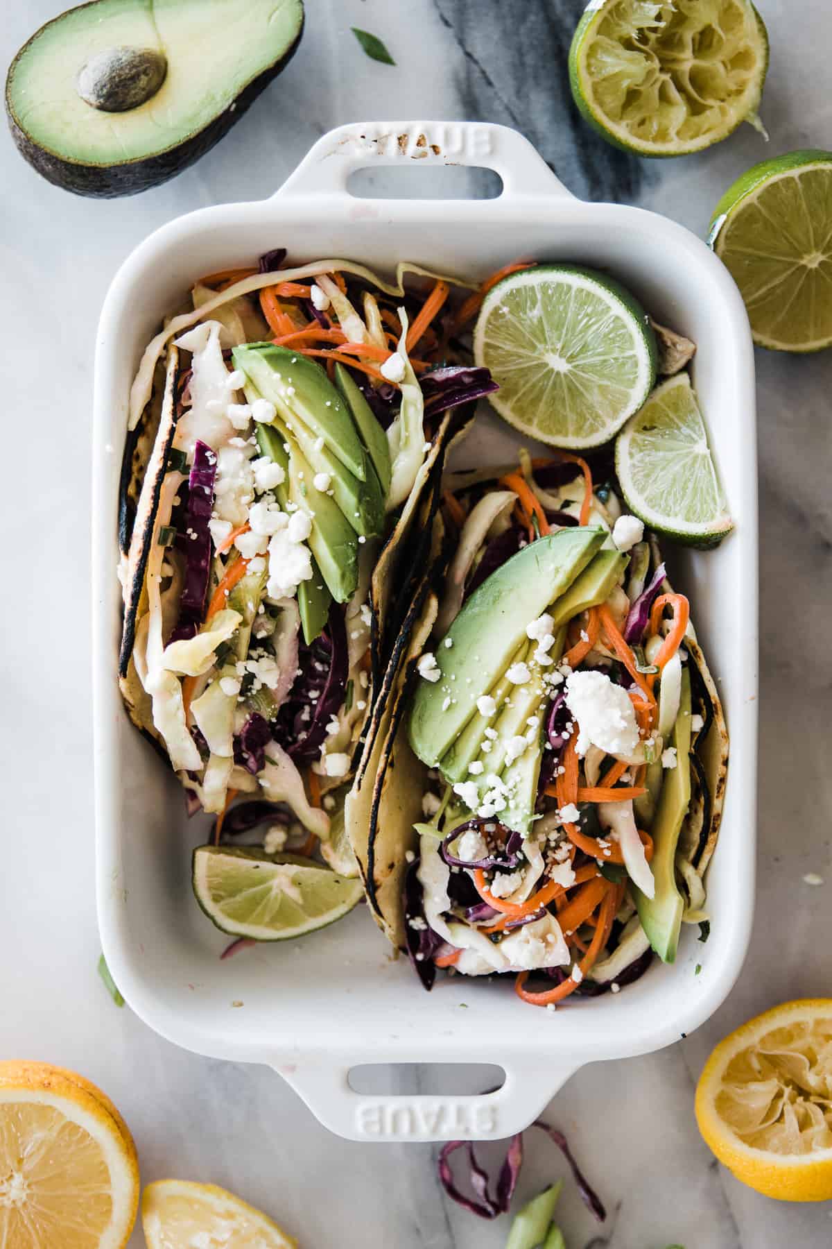 Two tacos topped with citrus slaw in a staub pan