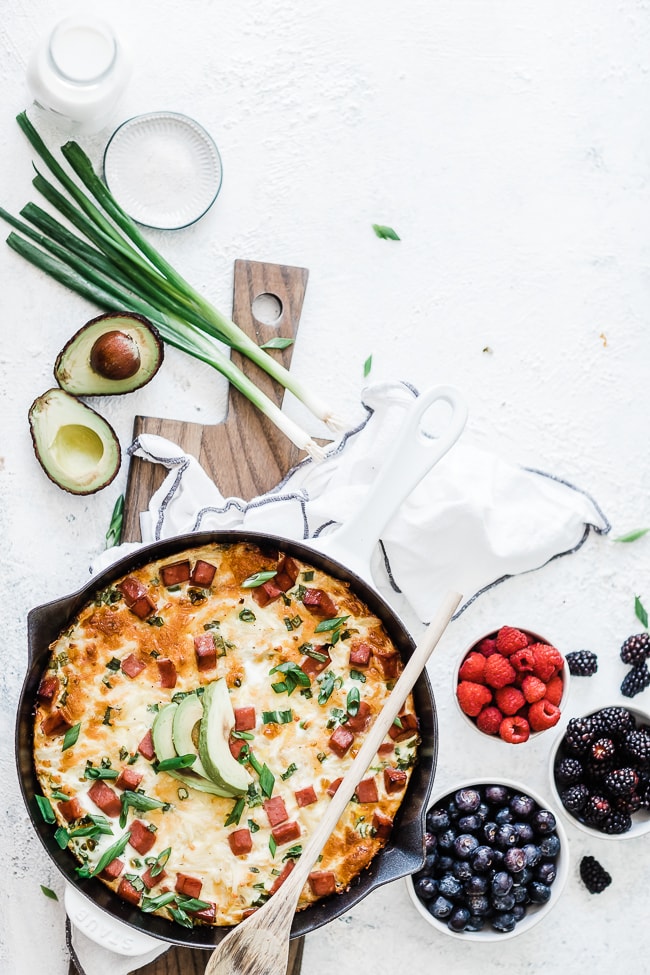 Ham & egg casserole in a cast iron skillet. - surrounded by berries.