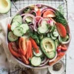 Cucumber tomato onion salad on the table on top of a wire rack with ingredients around the edges of the photo.