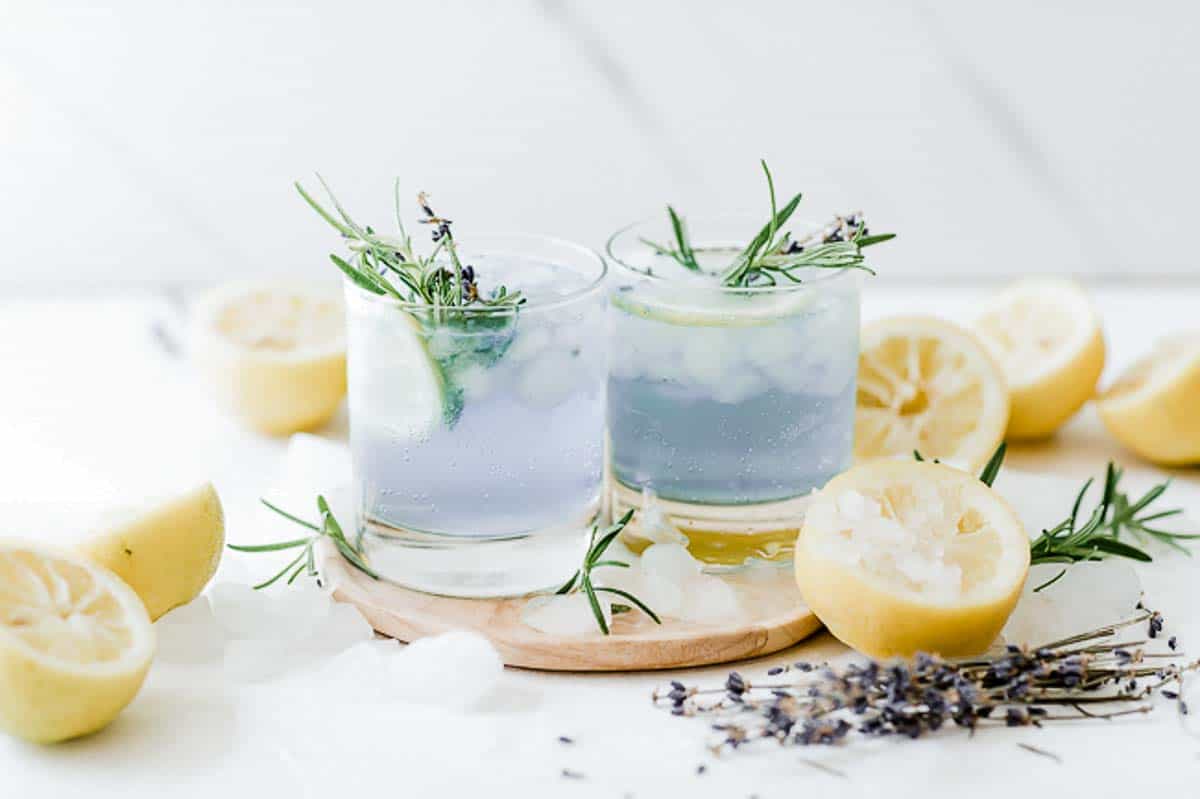 Sparkling lavender lemonade in glass glasses, surrounded by lemons.