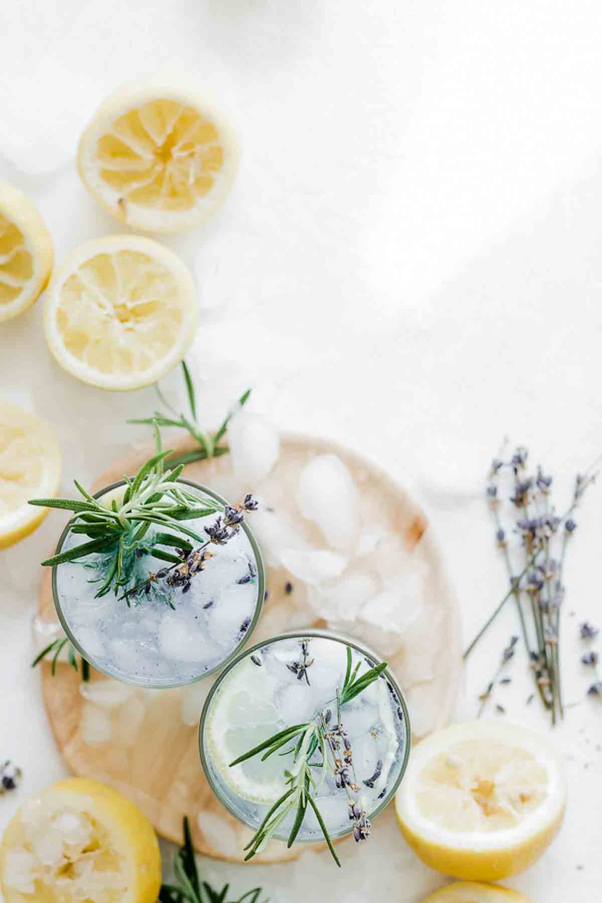 Glasses of homemade lavender lemonade on the table with fresh herbs and lemons.