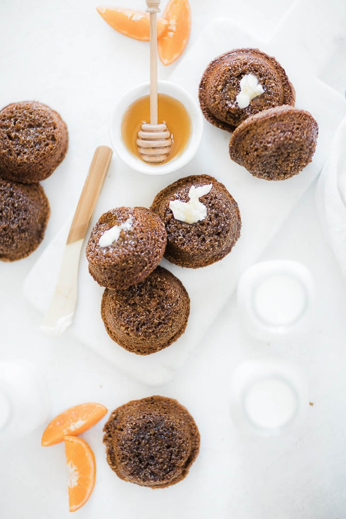 Molasses bran muffins on a table with oranges and jars of milk.