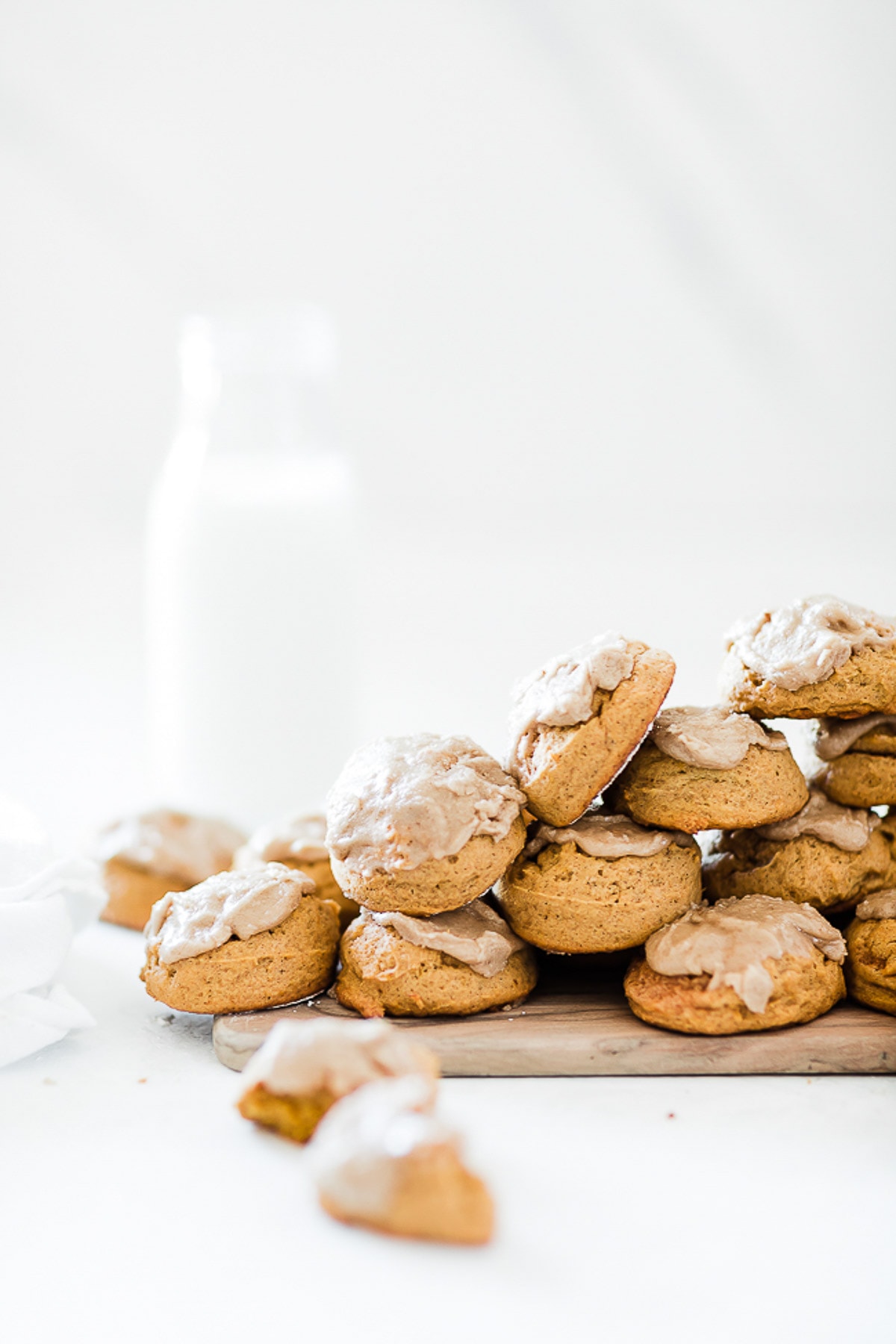 Soft pumpkin cookies stacked on a wooden cutting board.