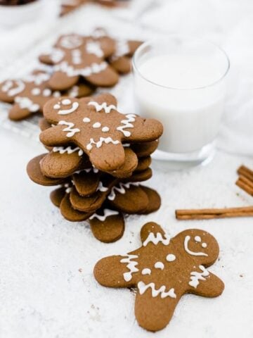 Easy gingerbread men recipe stacked next to a glass of milk.
