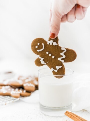 Easy gingerbread men recipe being dipped into a glass of milk.