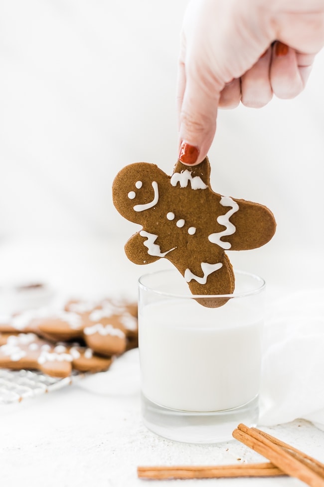 Easy gingerbread men recipe being dipped into a glass of milk.