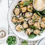 Artichoke spinach stuffed mushrooms in a white braiser.