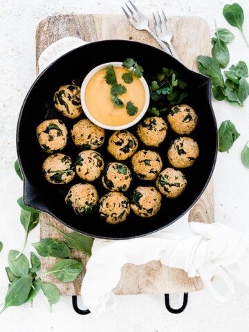 Spinach balls recipe in a cast iron skillet with mustard dipping sauce to the side.