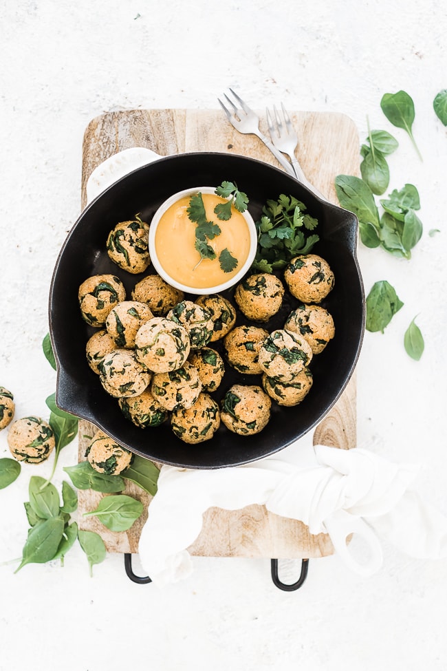 Spinach balls recipe in a cast iron skillet with mustard dipping sauce to the side.
