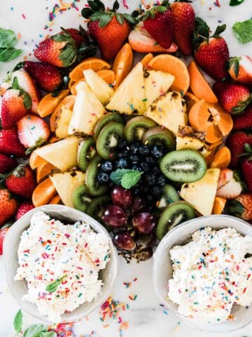 Funfetti cake batter dip on a tray of crackers and fruit.