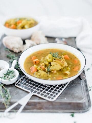 Golden chicken stew in a white rimmed bowl atop a wire cooling rack.