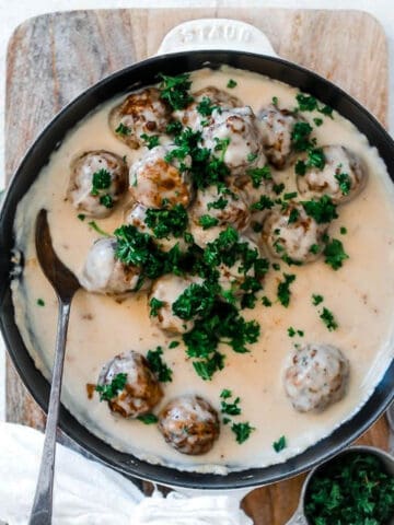 Swedish meatballs in a cast iron skillet garnished with chopped parsley.