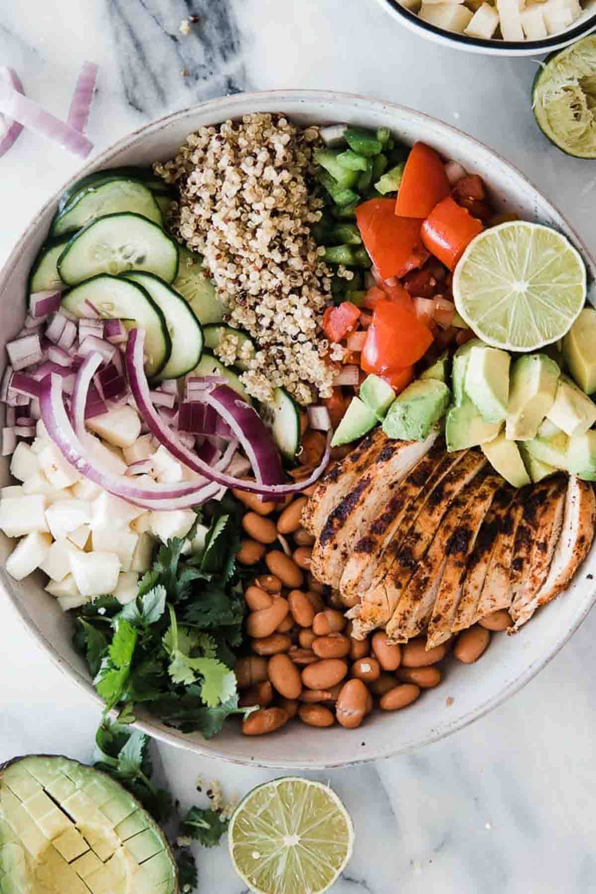A quinoa bowl on the table with all the ingredients in the bowl in groups.