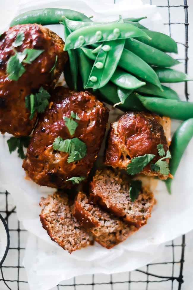 Mini meatloaves on a wire cooling rack, with a side of sugar snap peas.