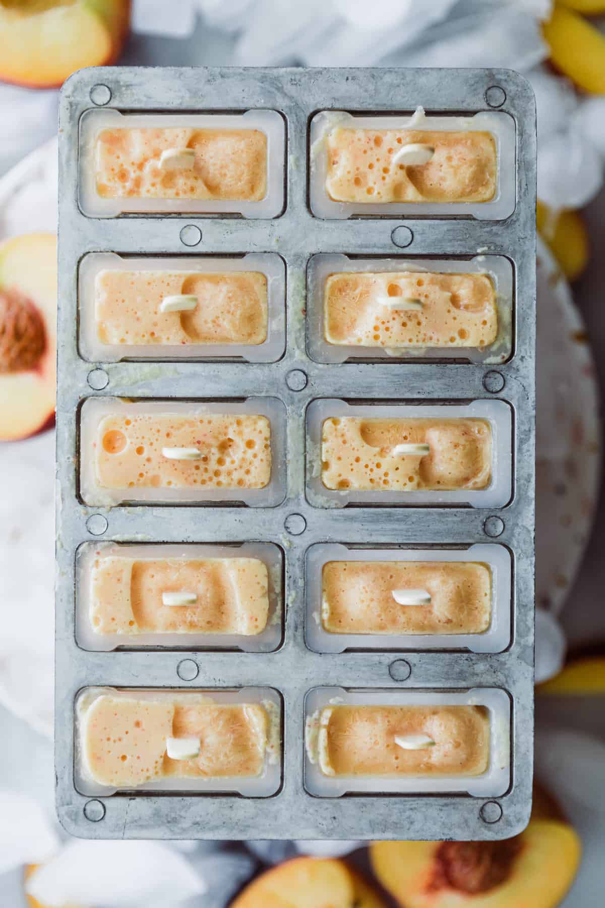 Peach Popsicles frozen in mold with popsicle sticks. 