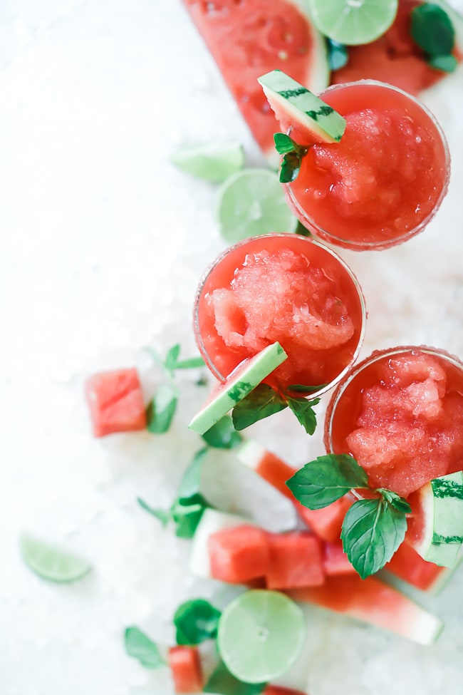 Birds eye view of coconut lime watermelon slush. Glasses are garnished with watermelon wedges and mint.