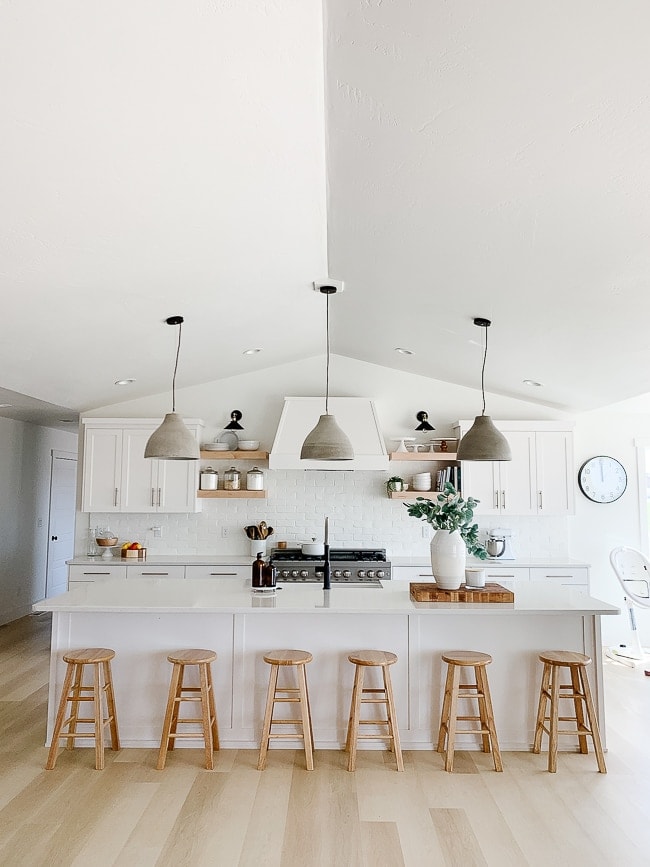 kitchen with white bar and 6 barstools, hanging cement pendants
