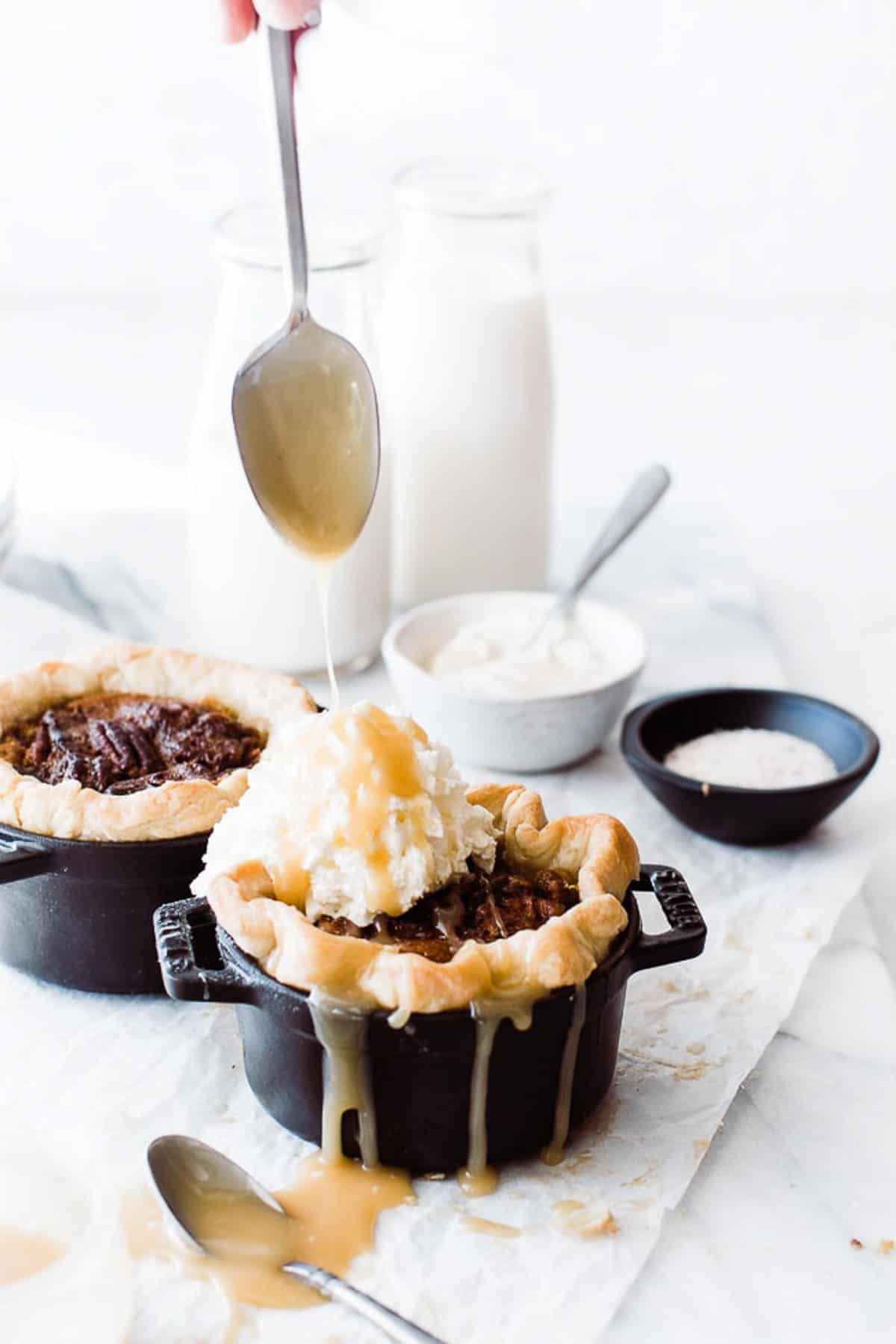 spoon drizzling caramel sauce over the individual pies