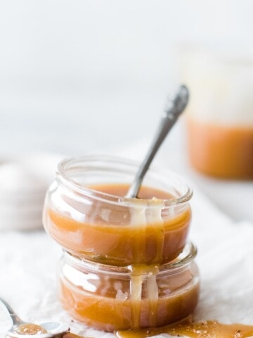 two glass jars of caramel with one spoons
