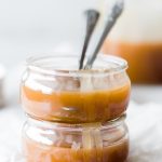 two glass jars of caramel with two spoons