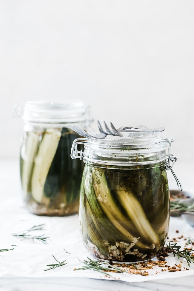 2 glass hinged jars filled with Garlic dill pickle recipe. One is set in from and the other in the background.