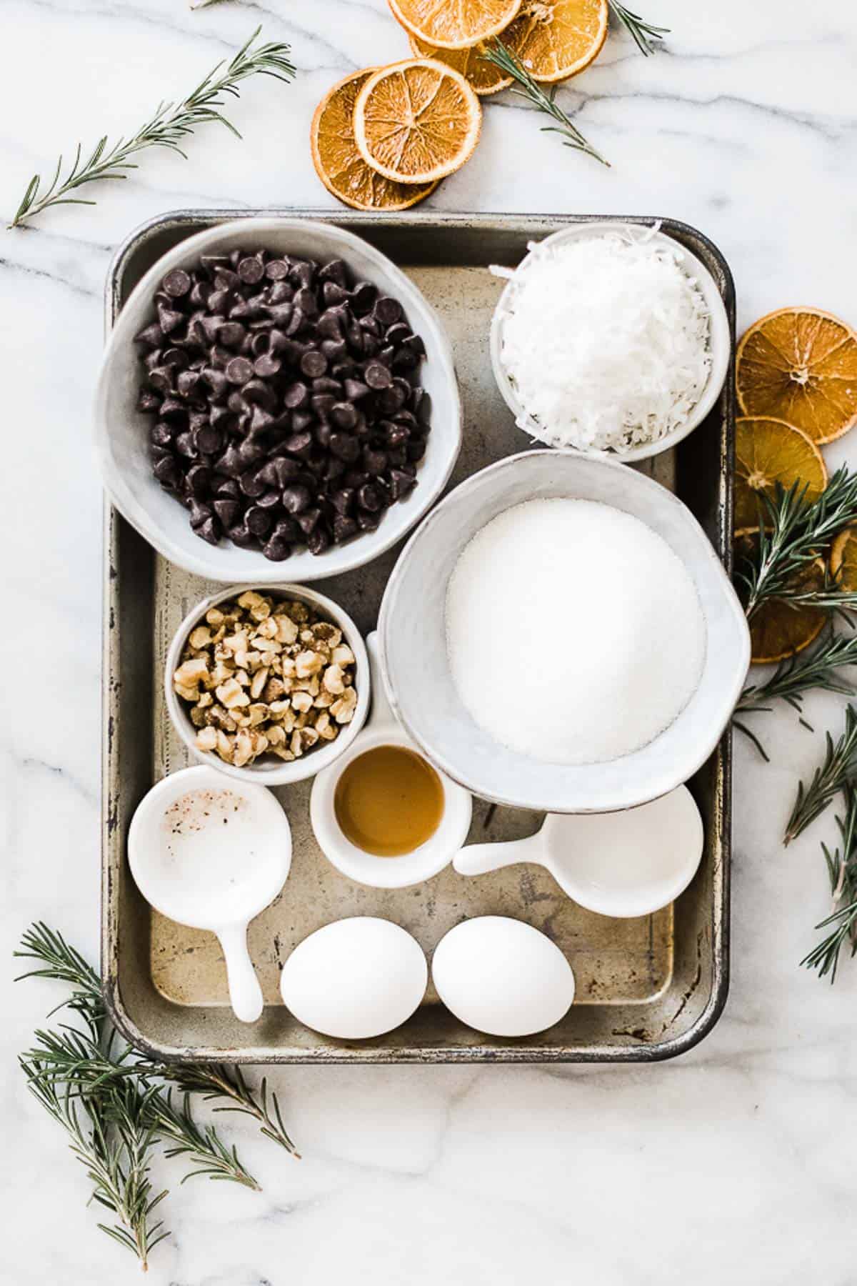 Ingredients needed to make chocolate meringue cookies on a metal baking tray.