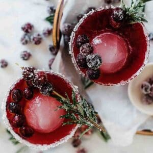 Glasses of sparkling cranberry mocktails with the rim sugared on a copper tray.