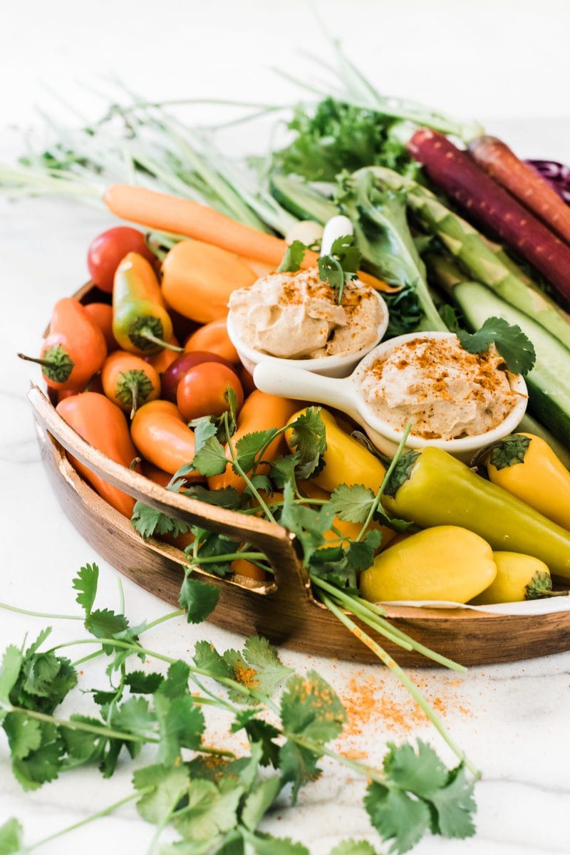 A ¾ angle of a rainbow of veggies on a platter. There are two small bowls of fiesta ranch dip.