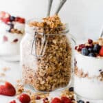 A jar of healthy granola with honey and oats on the table with spoons in it for serving.