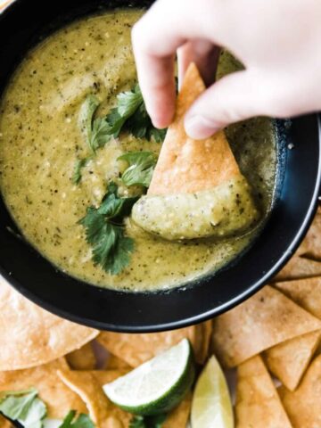tomatillo salsa verde in bowl with chip dipping