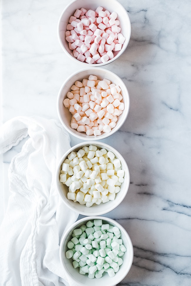 colored marshmallows separated by color in white bowls.