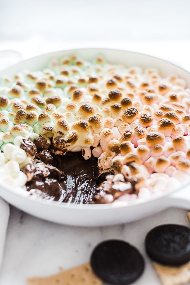 S'mores dip recipe in a white braiser with a large scoop scooped out.