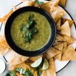 Roasted tomatillo salsa verde in black bowl with chips.
