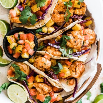 Grilled shrimp tacos on a copper platter. They are garnished with cilantro and lime.