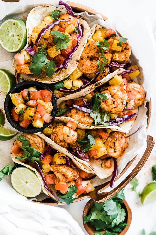 Grilled shrimp tacos on a copper platter. They are garnished with cilantro and lime.