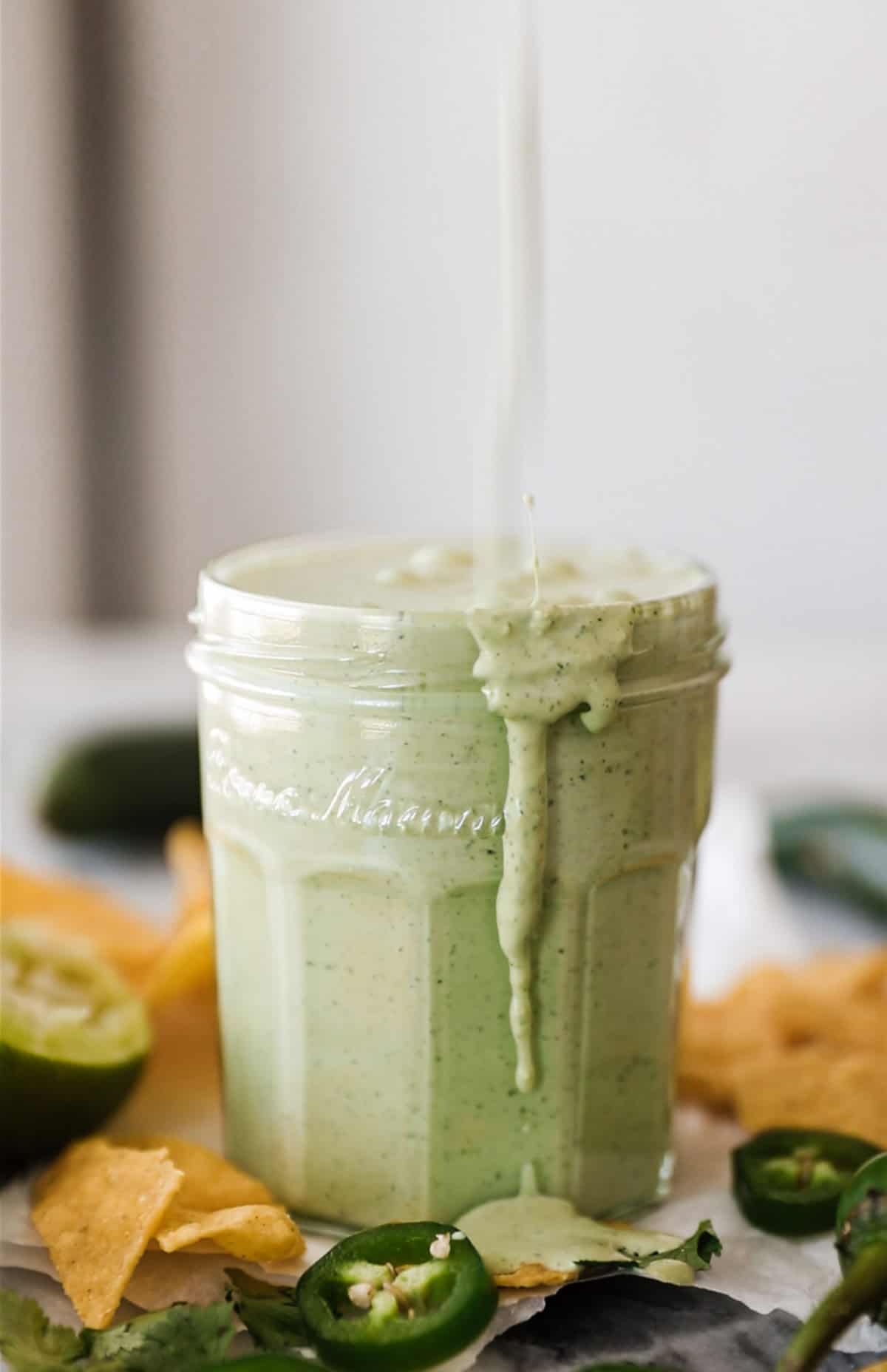 Creamy Jalapeno sauce being poured into a glass jar.