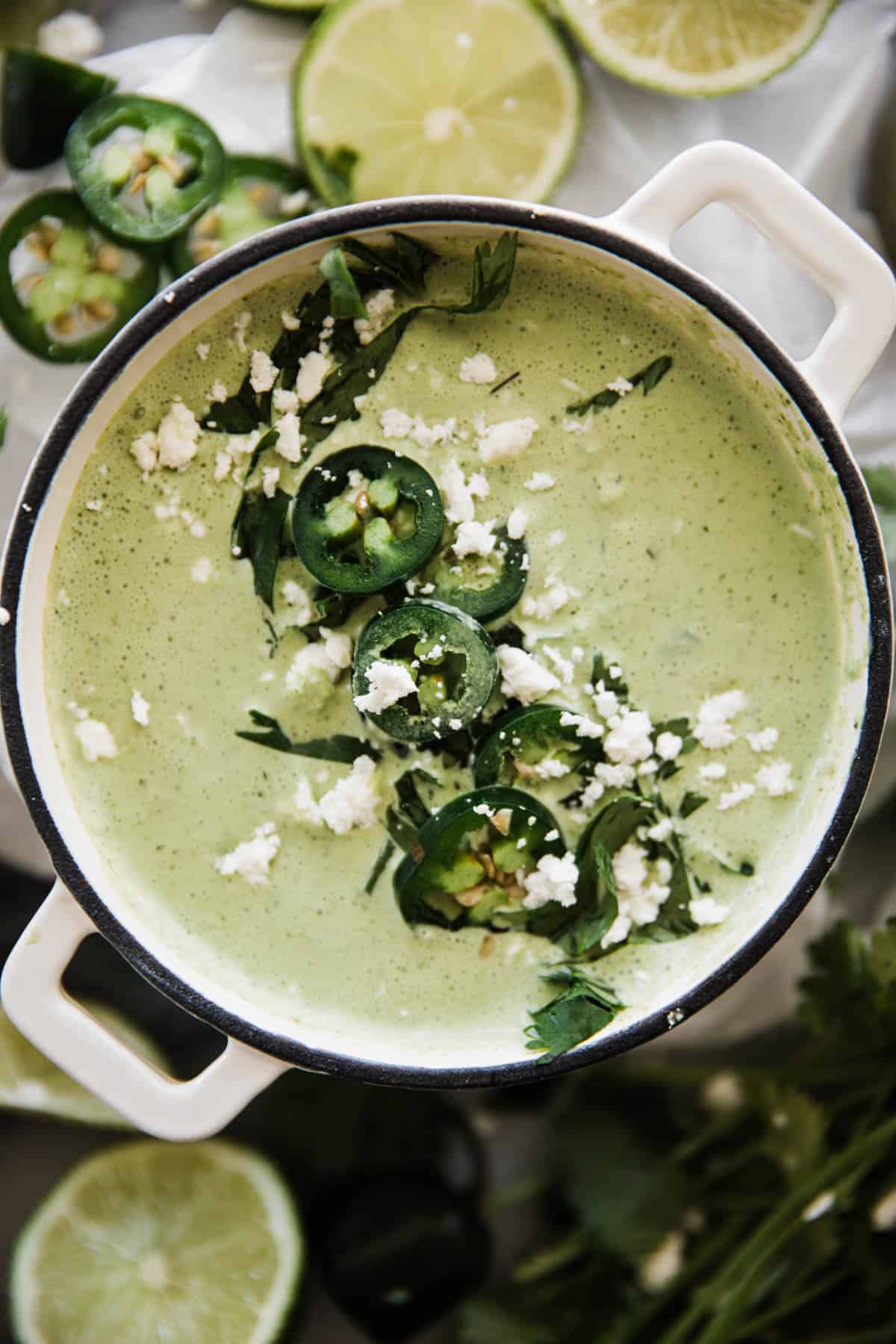 Creamy jalapeno sauce in a bowl topped with cilantro, fresh jalapeño and cheese.