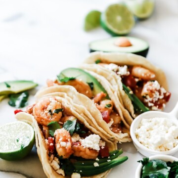 A ¾ view of easy shrimp tacos garnished with cilantro and cotija.