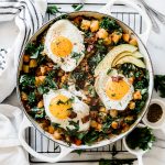 Potato hash recipe in a white braiser. It is set atop a wire cooling rack and topped with sunny side eggs.