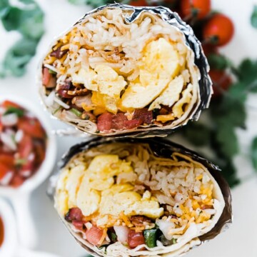 A close up of best breakfast burrito wrapped in foil and cut in half.