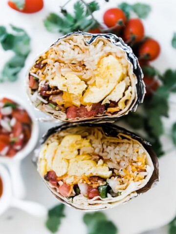 A close up of best breakfast burrito wrapped in foil and cut in half.
