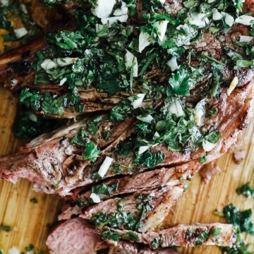 grilled lamb chop with chimichurri cut on wooden cutting board