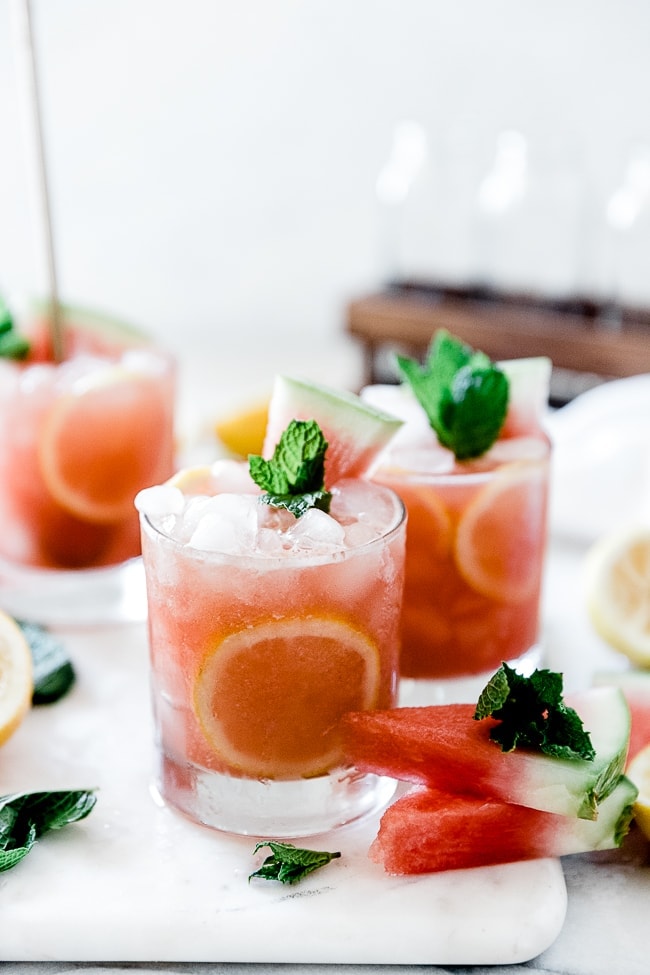 Watermelon lemonade in short glasses, garnished with mint and watermelon.