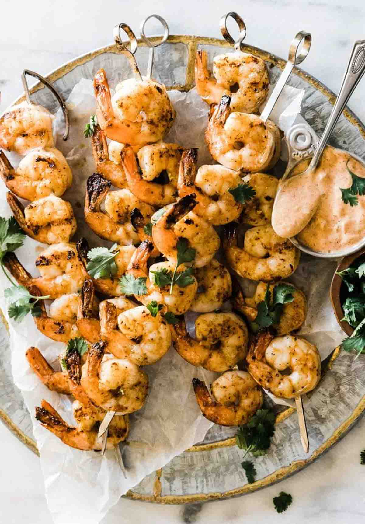 Shrimp on the barbie on a silver platter, garnished with cilantro.