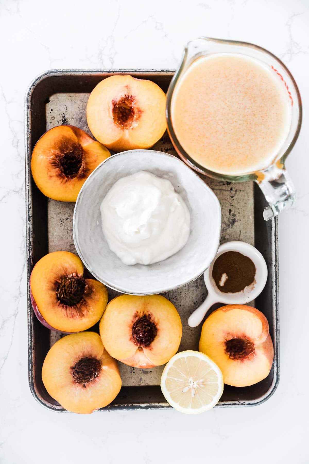 Peaches, mango nectar and yogurt on a metal baking tray.