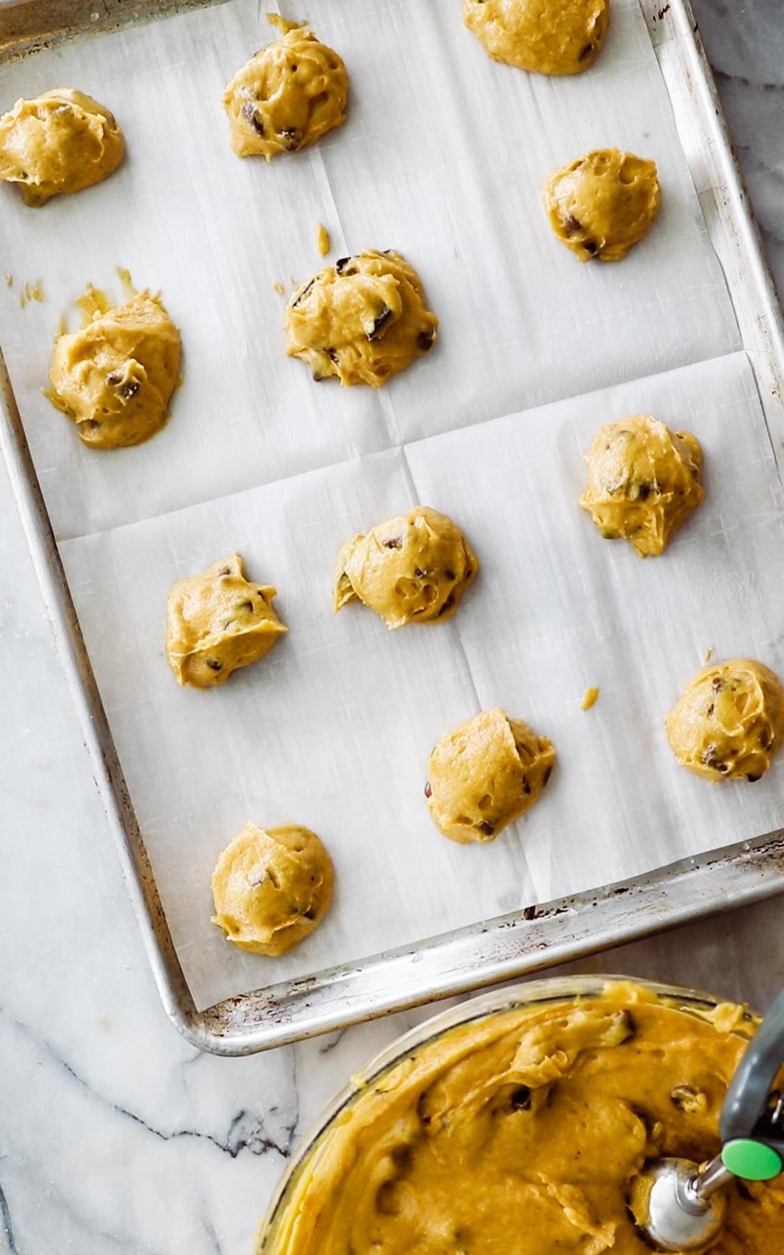 raw cookie dough balls on parchment paper lined cookie sheet. 