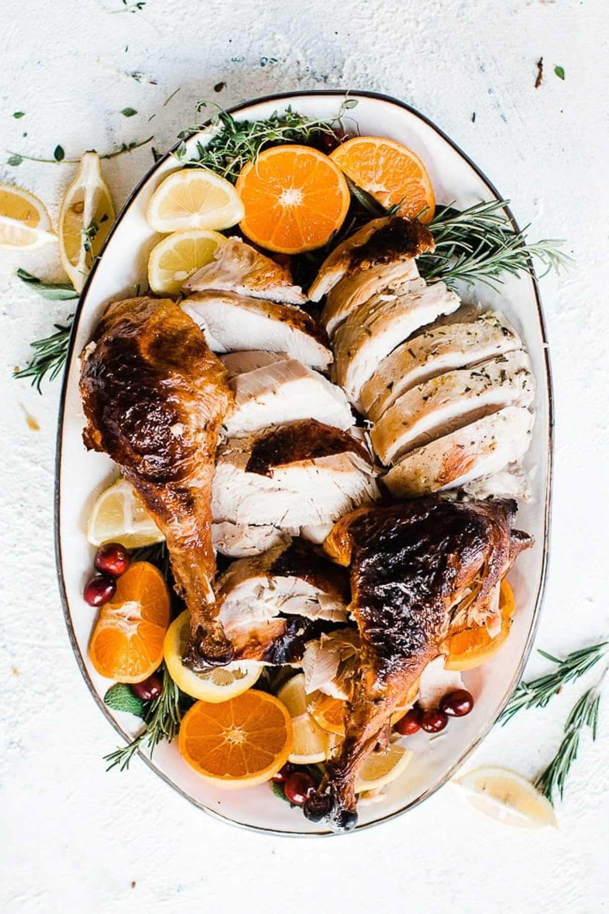 Carved turkey on a platter, garnished with oranges.