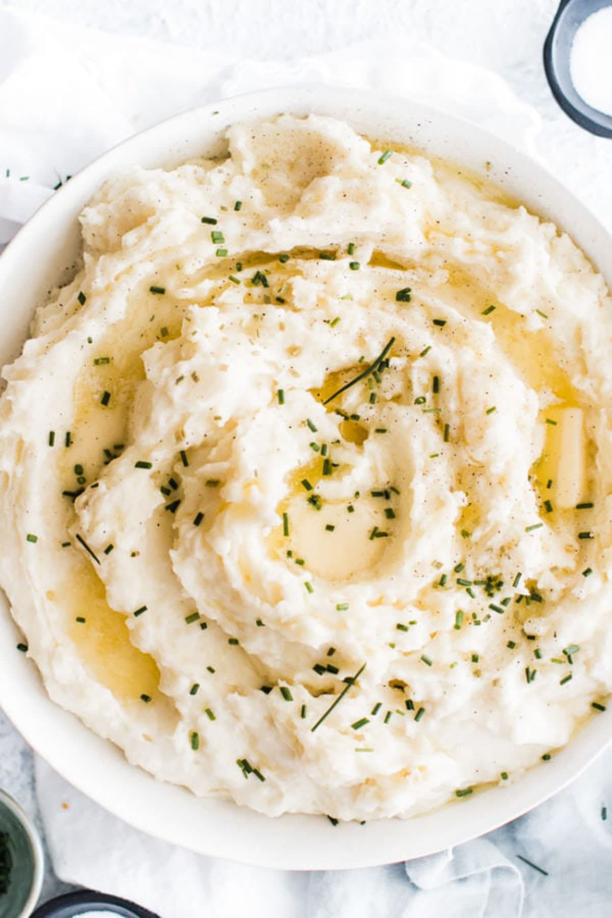 Pressure cooker mashed potatoes in a white bowl topped with chives.